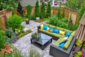 Lush garden patio with colorful cushions on a green sectional sofa.