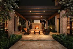 Outdoor patio with a wooden pergola, stone fireplace, and cushioned seating.